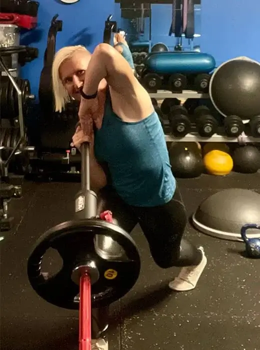 Woman lifting weighted bar during personal training session